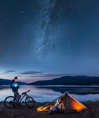 couple under the milky way camping at lake people in nature