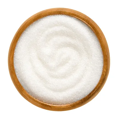 fine granulated white sugar in wooden bowl over white