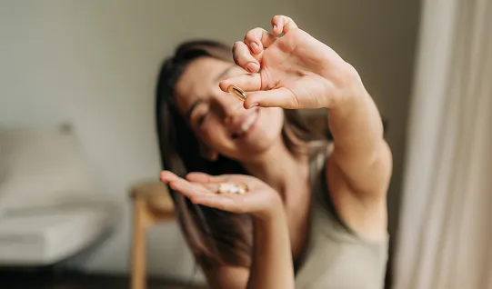happy smiling woman holding an omega pill in her hand