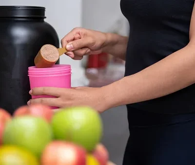 healthy women preparing a whey protein after doing weight training in the kitchen with fresh