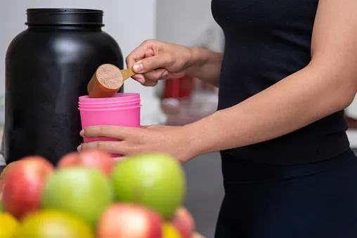 healthy women preparing a whey protein after doing weight training in the kitchen with fresh