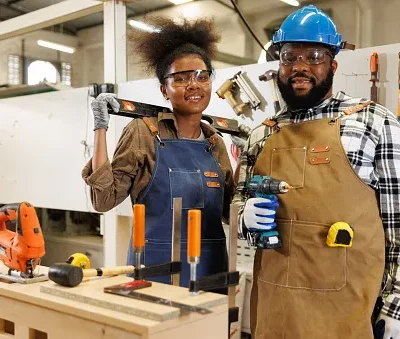 portrait young woman and black man carpenter holding the tools in factory