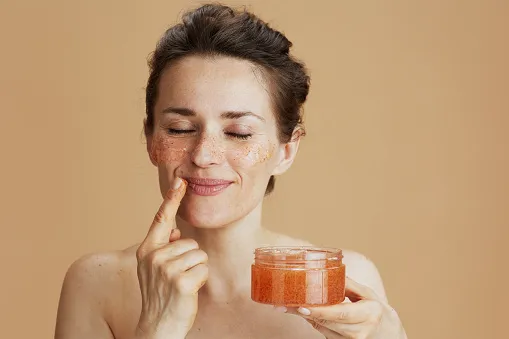 relaxed modern woman with face scrub isolated on beige