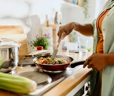 woman preparing quinoa vegetable mix cooked in a frying pan