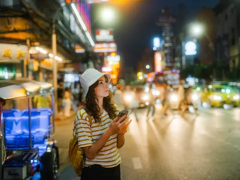 woman using smartphone while exploring chinatown in bangkok during vacation