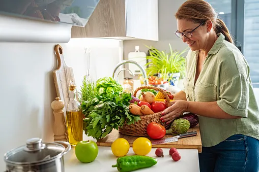 woman with basket full of fresh vegetables in kitchen