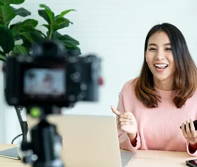 young attractive asian woman blogger or vlogger looking at camera and talking on video