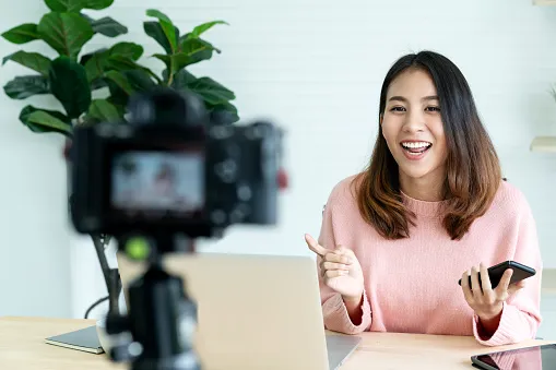 young attractive asian woman blogger or vlogger looking at camera and talking on video